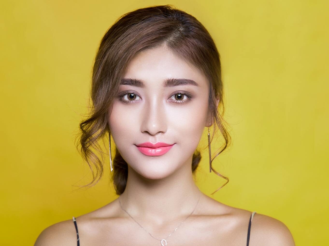 Beautiful portrait of a woman with elegant hairstyle on a vibrant yellow background.