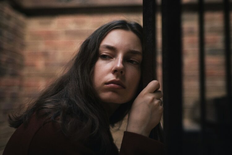 A woman leaning against a fence with her eyes closed