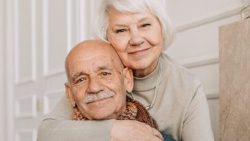 Elderly couple enjoying a warm and loving moment indoors, drinking together.