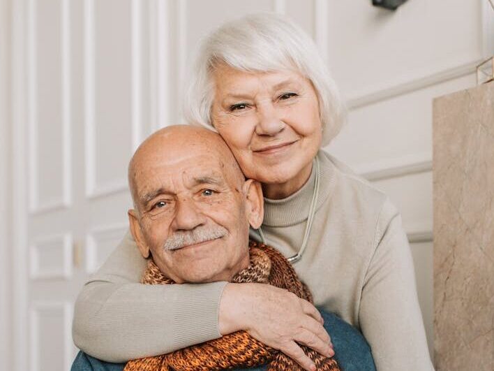 Elderly couple enjoying a warm and loving moment indoors, drinking together.