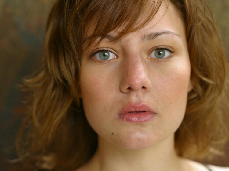 A close-up portrait capturing a young woman's natural beauty with a serious expression.