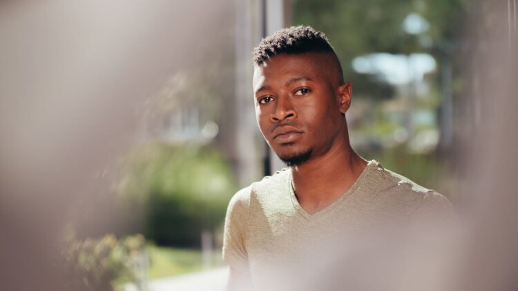 A pensive young man gazing into the distance on a sunny day.