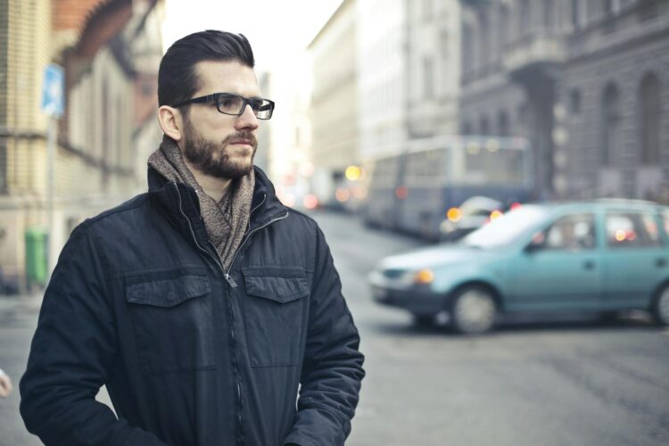 Fashionable man with glasses standing on a bustling street in Budapest, Hungary.