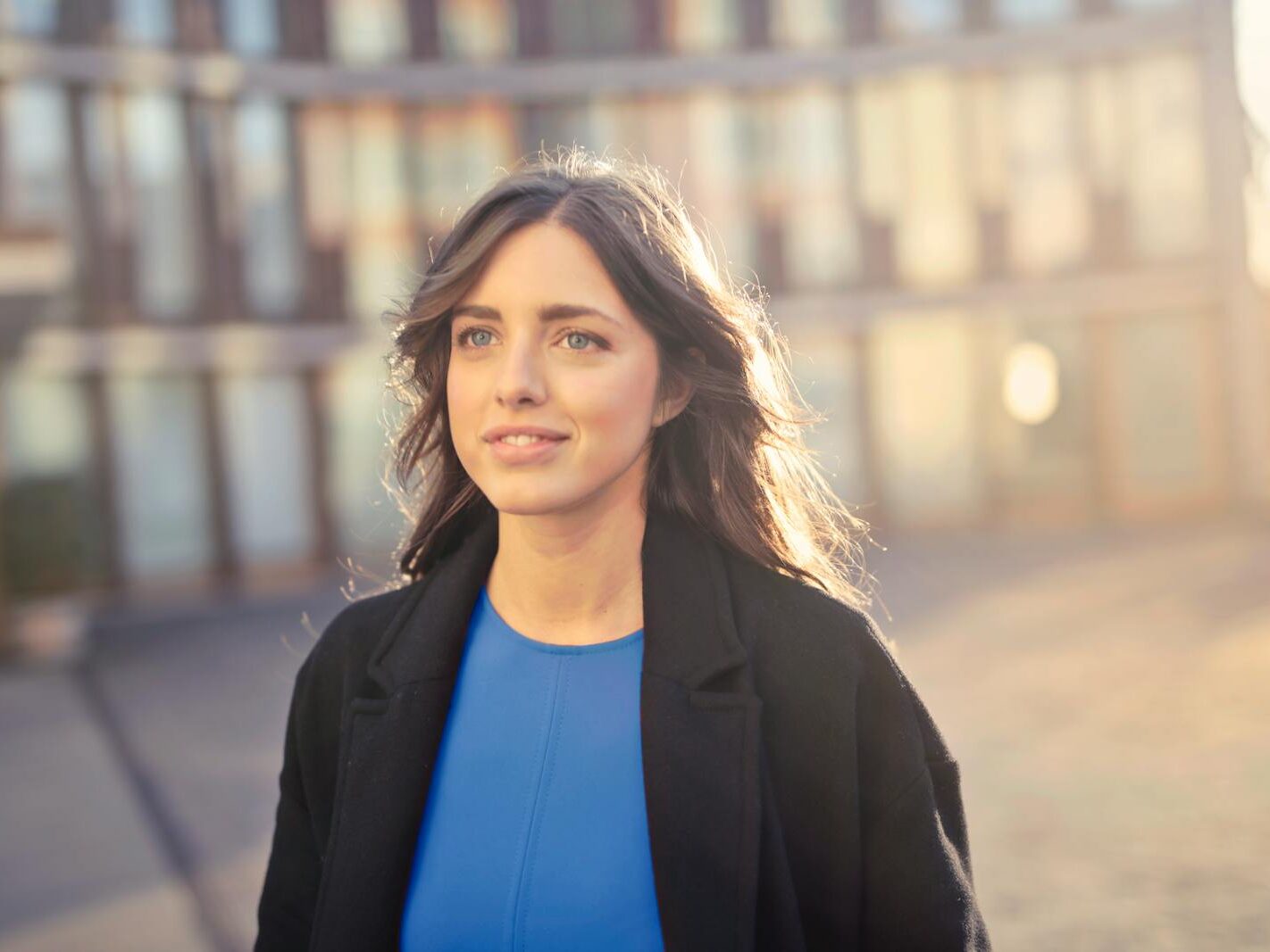 Portrait of a confident woman walking outdoors in an urban setting with a smile.