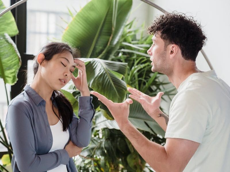 A man and woman having a heated argument indoors, surrounded by plants.