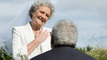 Elderly couple sharing a loving and romantic moment outdoors during their wedding.