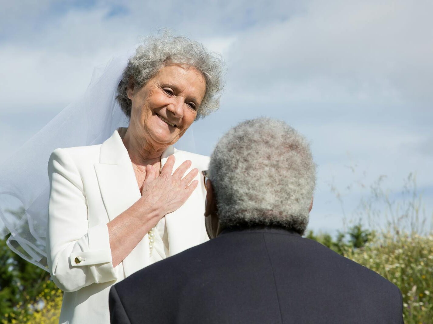 Elderly couple sharing a loving and romantic moment outdoors during their wedding.