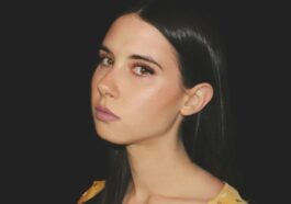 a woman with long black hair wearing a yellow top