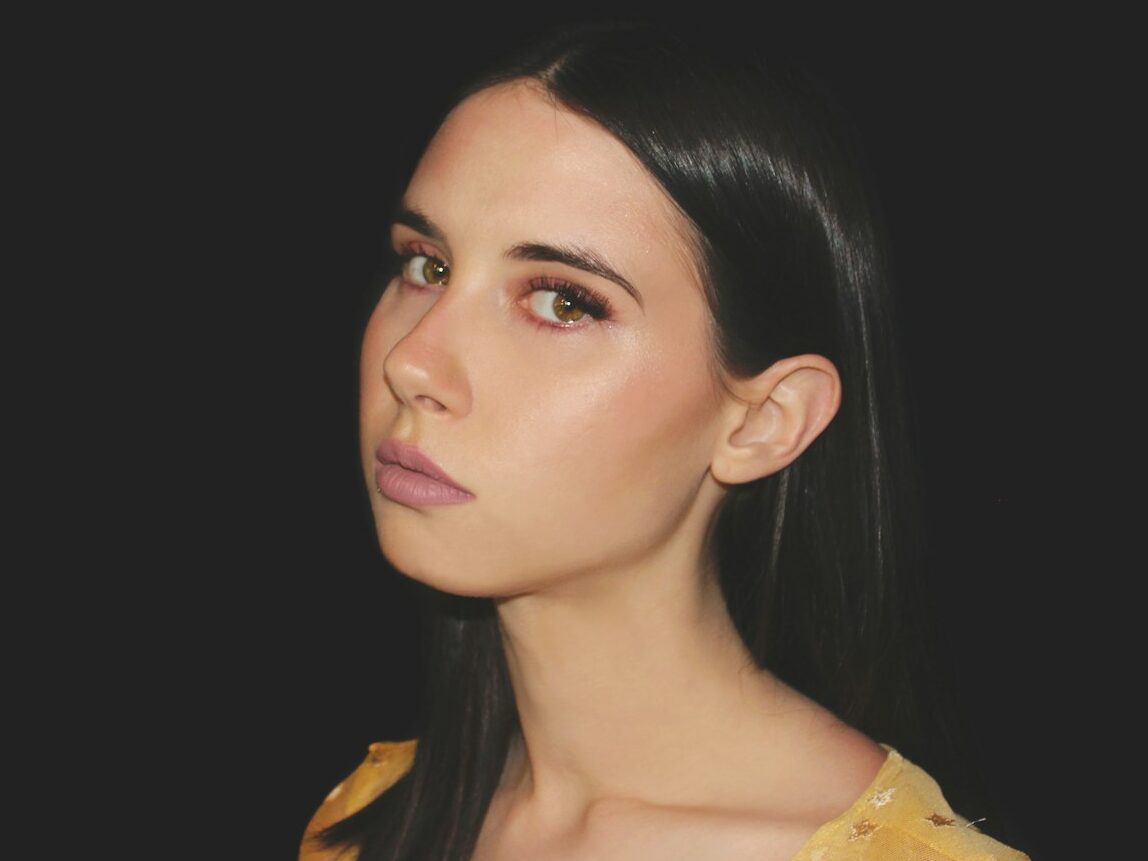 a woman with long black hair wearing a yellow top