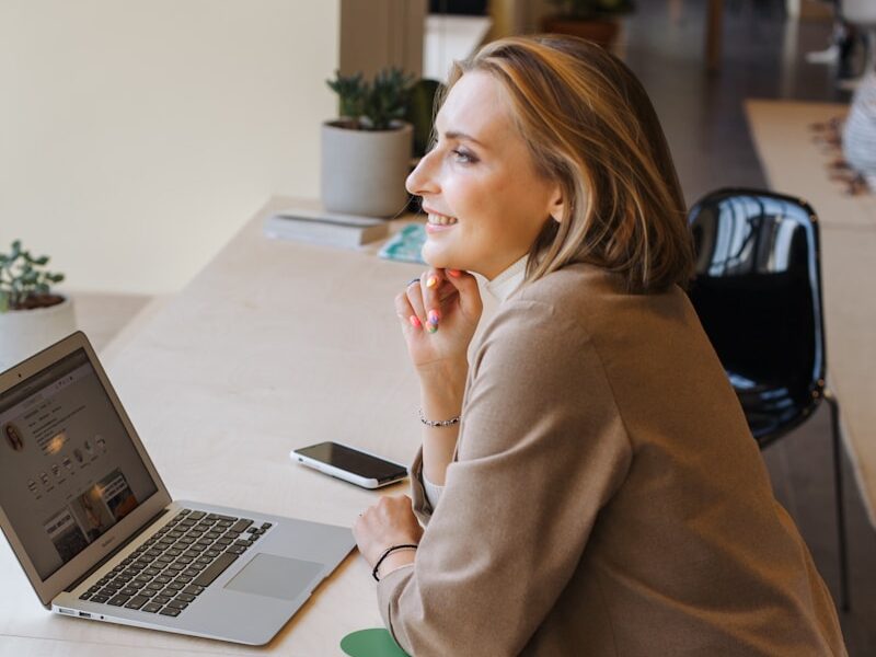 woman in brown coat using macbook air