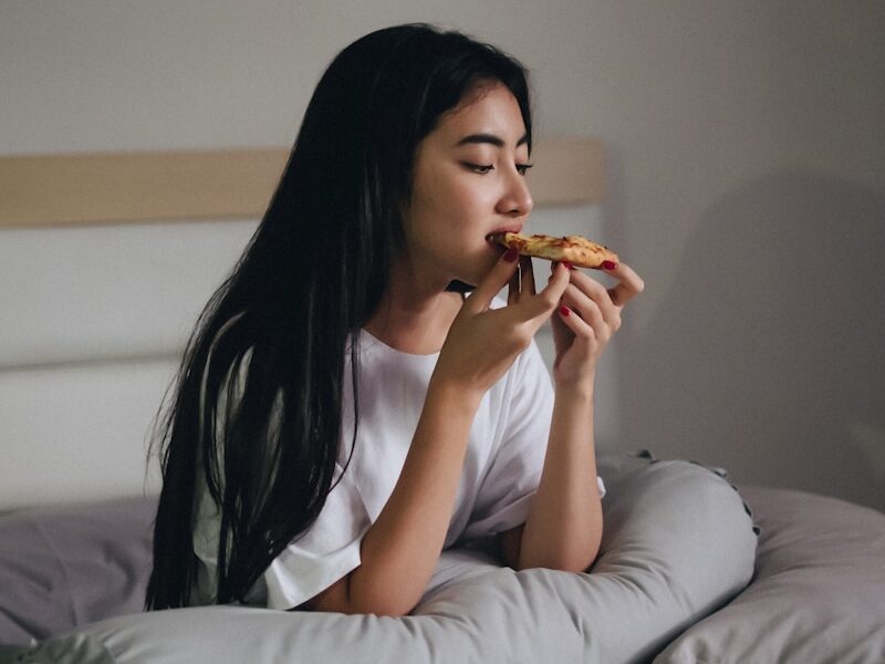 sitting woman in bed eating pastry