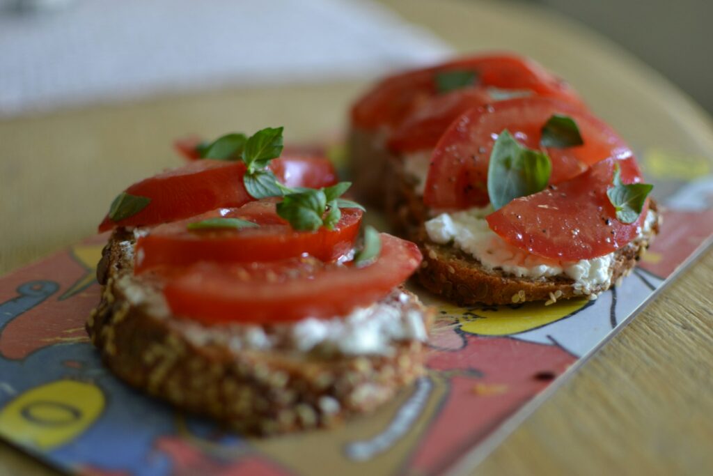 a couple of burgers with tomatoes and cheese on a plate