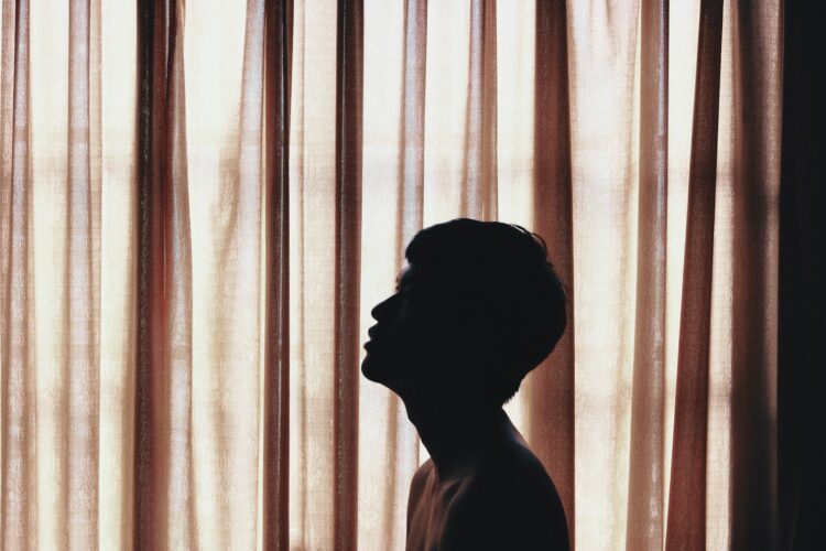 a silhouette of a person standing in front of a curtain