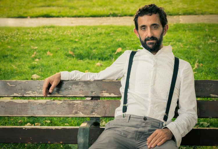man wearing white dress shirt sitting on outdoor bench