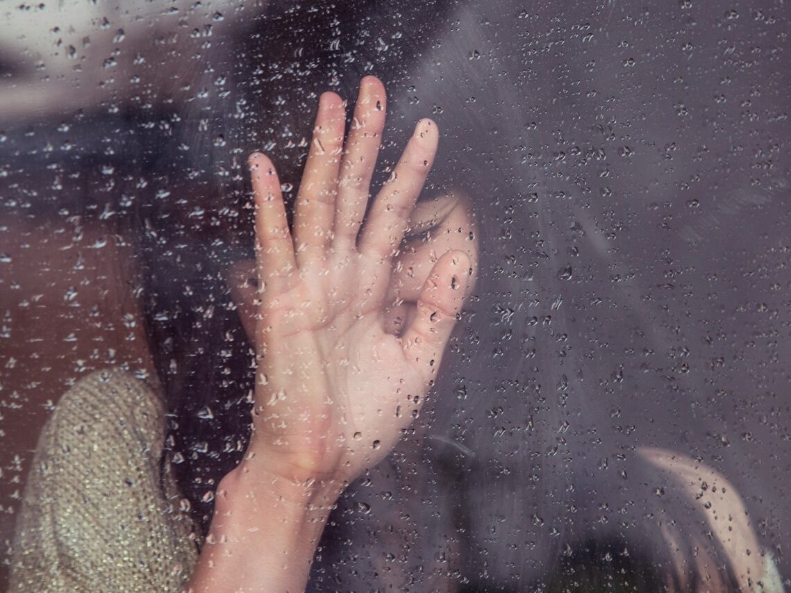 woman touch rainy glass