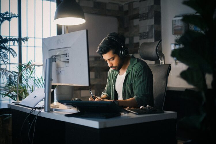 A man works intently at a computer desk.