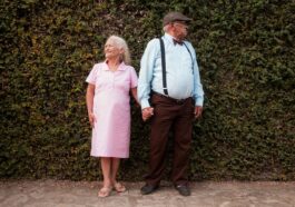 A man and a woman standing in front of a hedge
