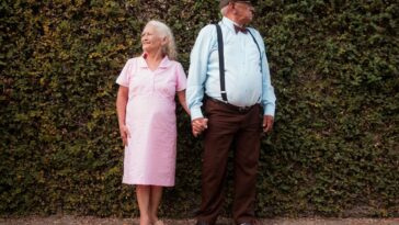 A man and a woman standing in front of a hedge