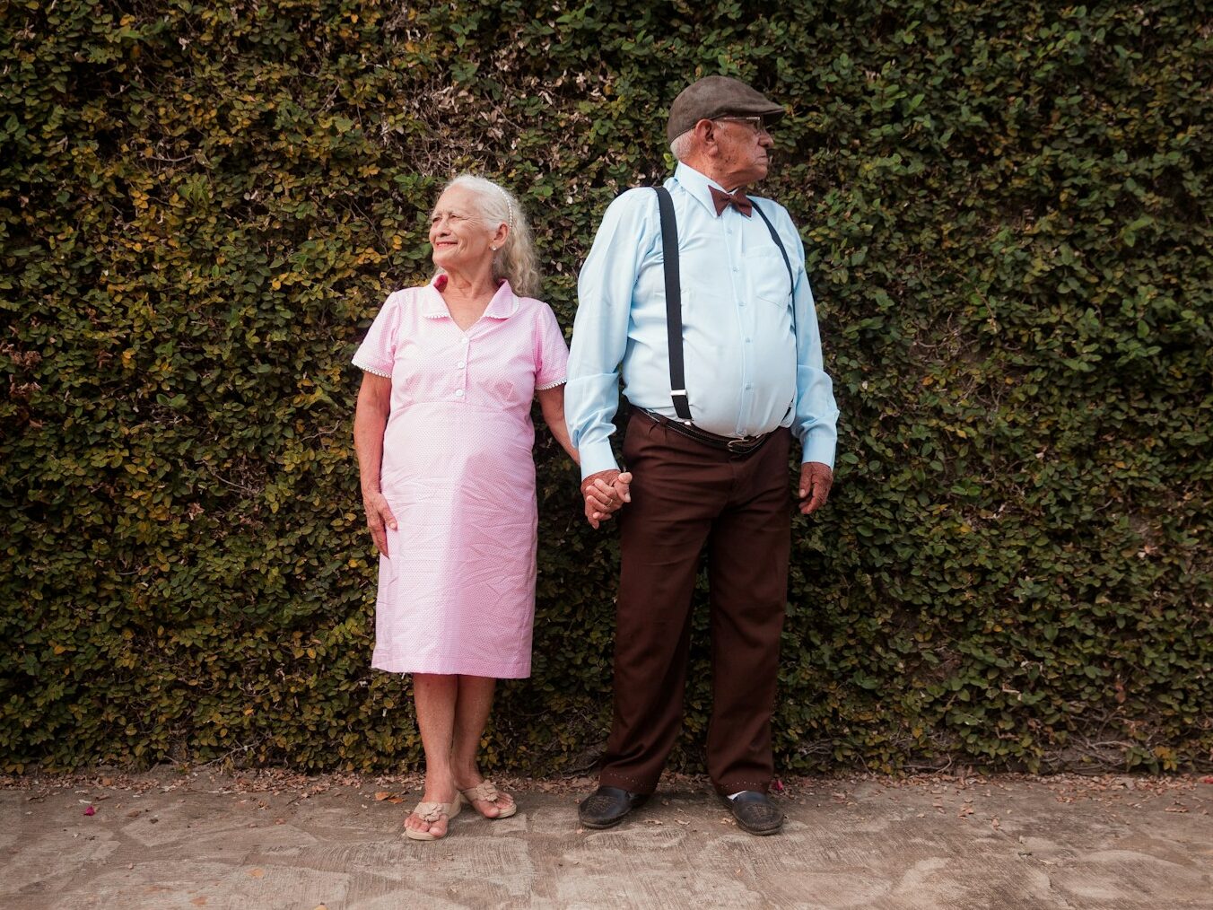 A man and a woman standing in front of a hedge