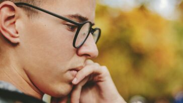 boy with black framed eyeglasses holding face