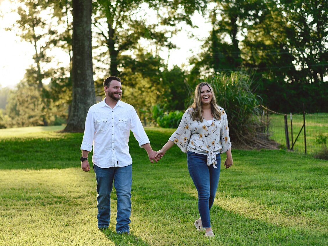couple walking at grass lawn away from tree