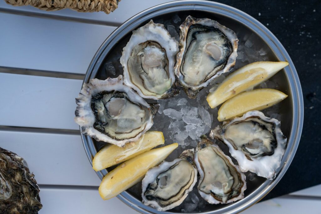 a metal pan filled with oysters and lemon wedges