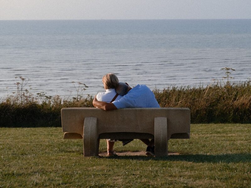 A man sitting on a bench looking at the ocean