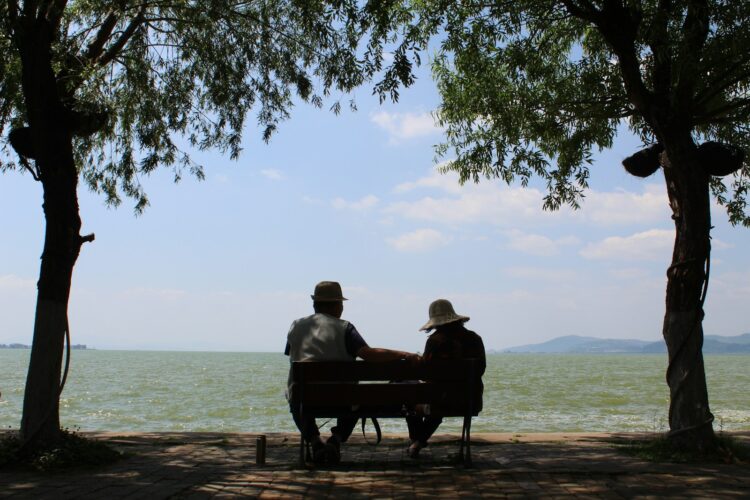 Two people sitting on a bench near the water