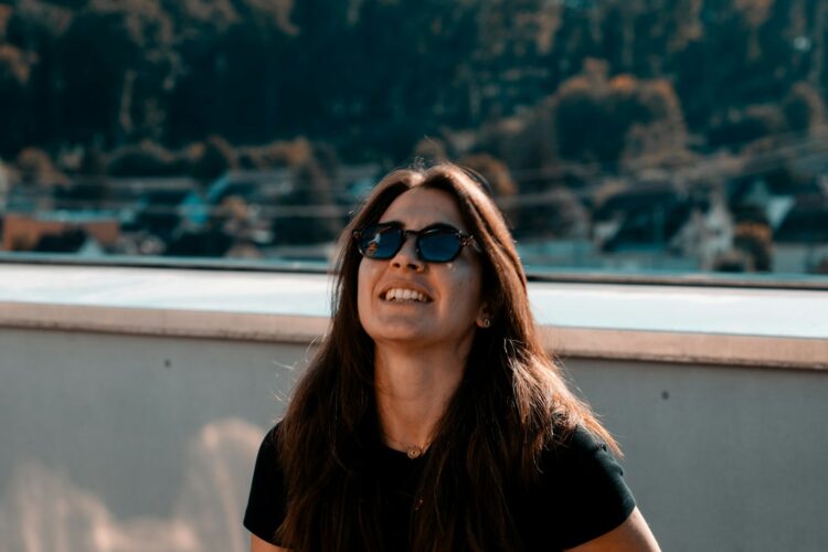A woman wearing sunglasses sitting on a ledge