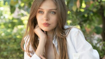 woman in white long sleeve shirt sitting on brown wooden bench