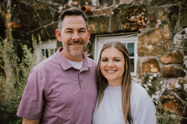 a man and a woman standing in front of a stone building