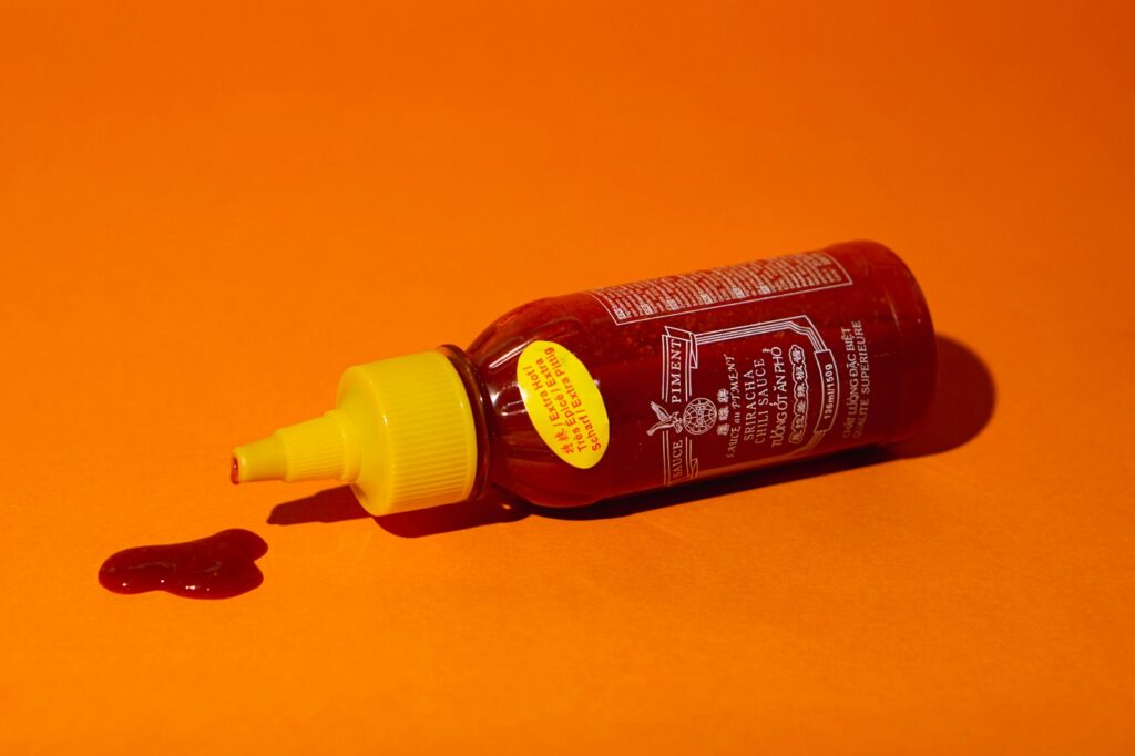 a bottle of ketchup sitting on an orange surface