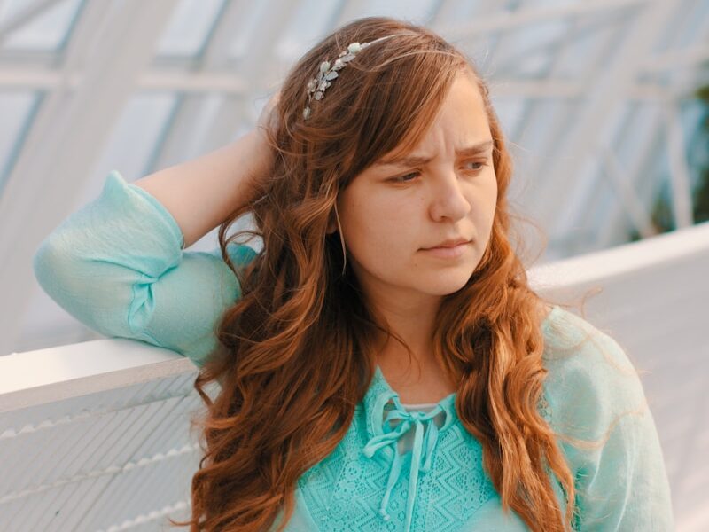 woman holding head near white handrail
