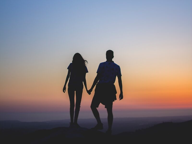 man and woman holding hands in silhouette photography