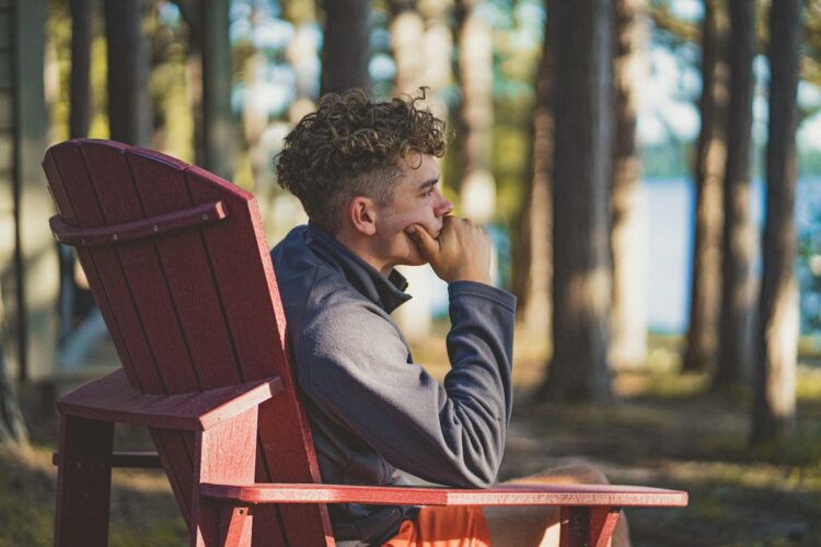a man sitting on a red bench in the woods