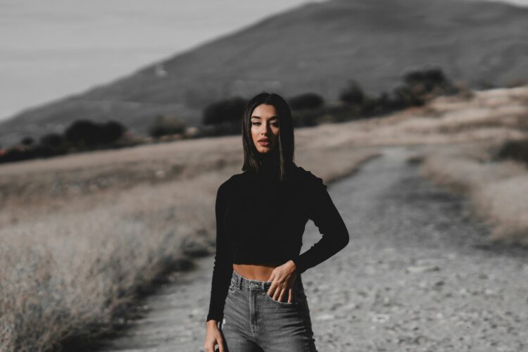 a woman standing on a dirt road with her hands on her hips