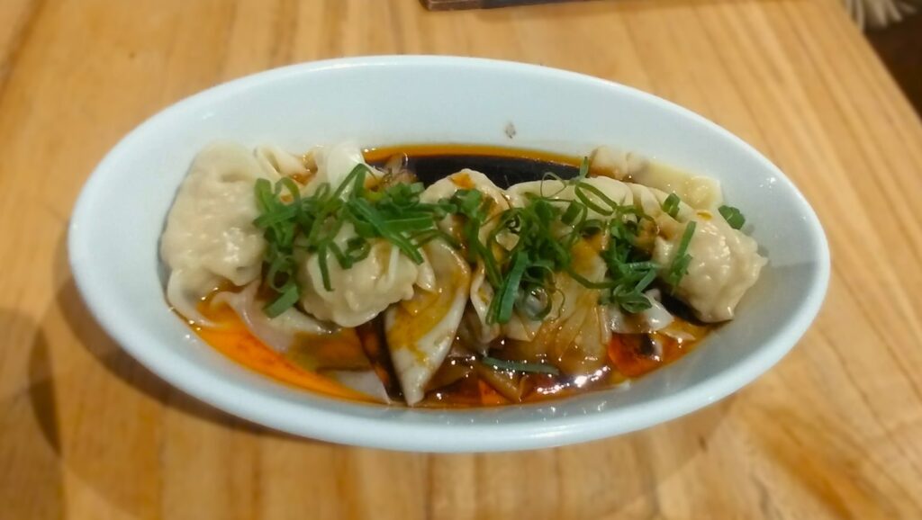 a white bowl filled with dumplings covered in sauce