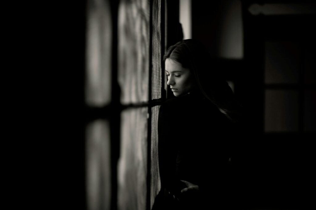 a woman leaning against a wall in a dark room