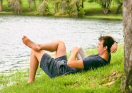 man on grass while reading book