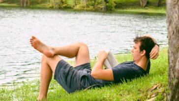man on grass while reading book