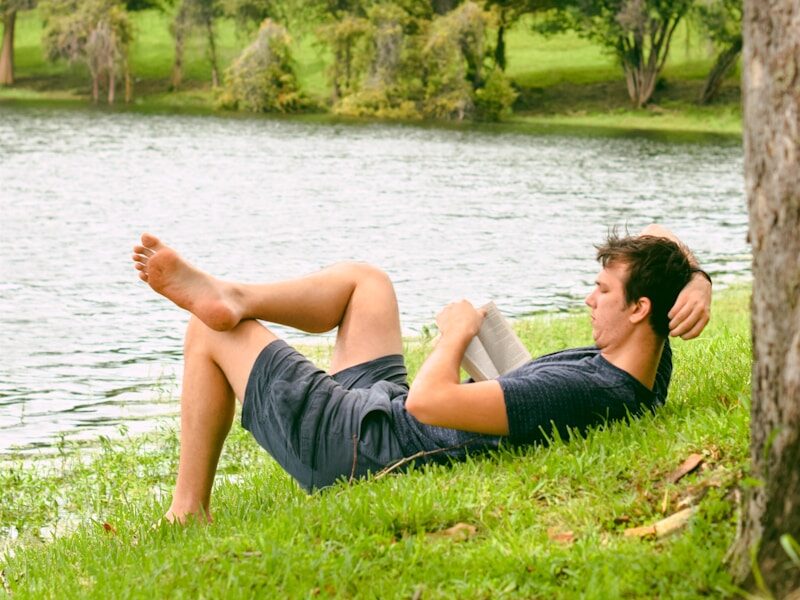 man on grass while reading book