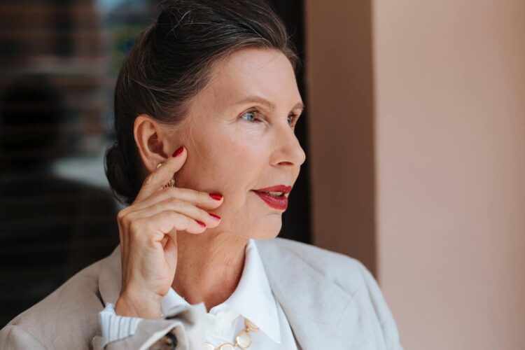 Portrait of an elegant senior woman with red lips and manicured nails, embodying grace and confidence.
