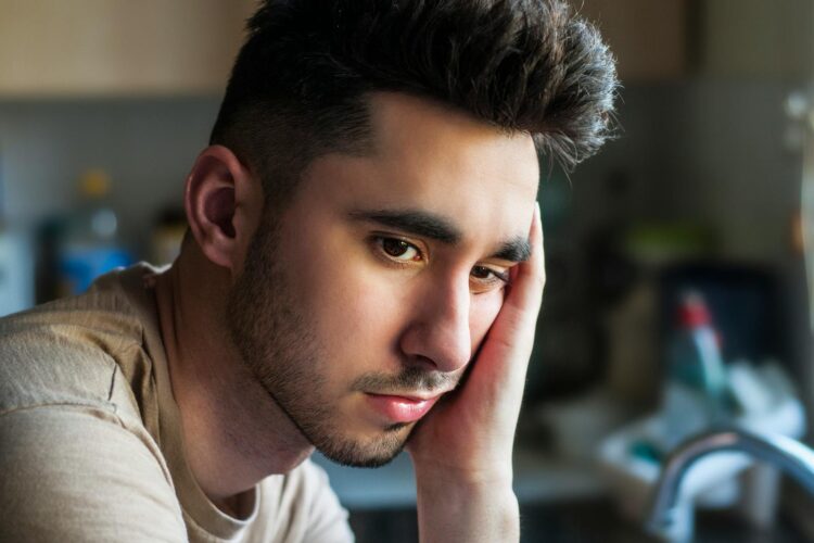Portrait of a thoughtful young man in casual wear, indoors with soft lighting.
