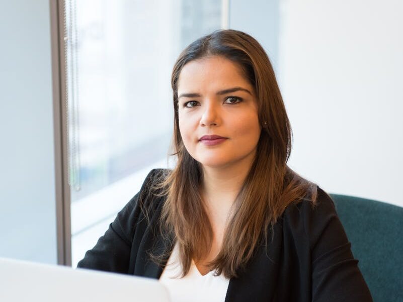 Confident businesswoman using laptop for remote work in a stylish office setting.