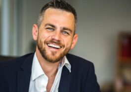 Business professional in suit smiling confidently in a modern office environment.