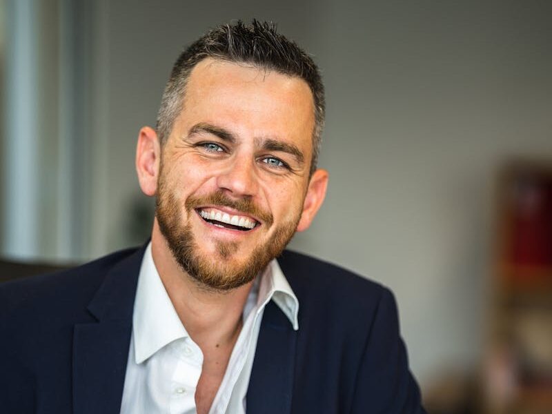 Business professional in suit smiling confidently in a modern office environment.