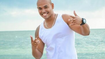 Smiling man in white clothing enjoying a day at the beach in Recife, Brazil.