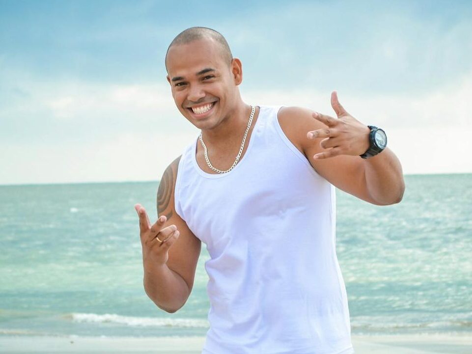 Smiling man in white clothing enjoying a day at the beach in Recife, Brazil.