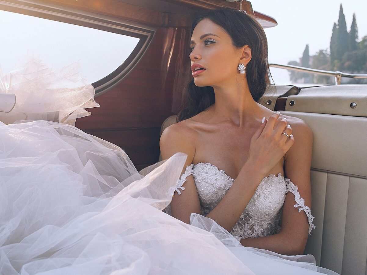 woman wearing white sweetheart-neckline wedding dress inside vehicle