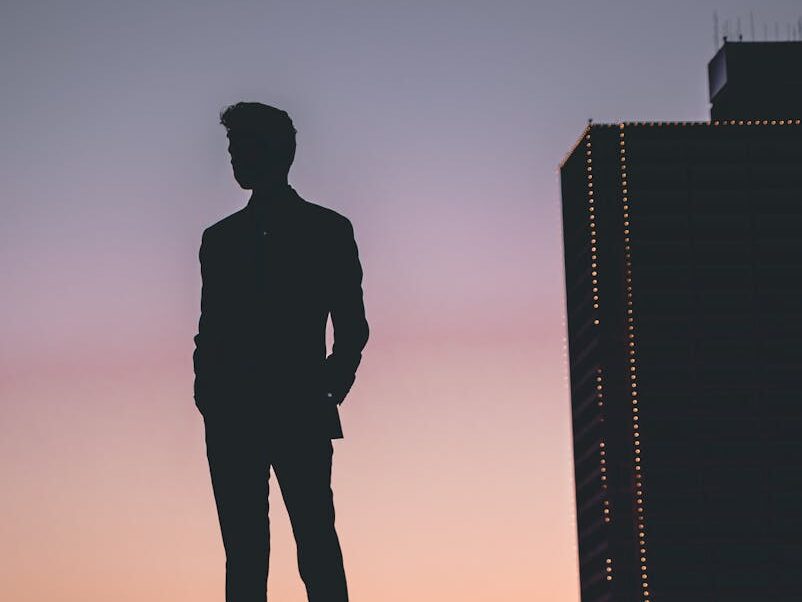 Silhouette of a man standing against a colorful Fort Worth sunset skyline, capturing urban tranquility.